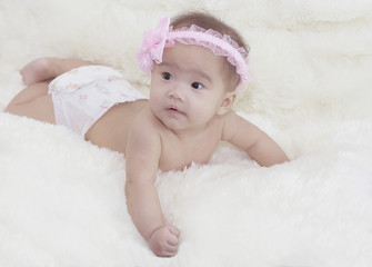 Cute baby with  pink bow is lying in the living room. Little Ang