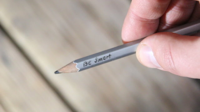 Be smart - inscription on a gray pencil. Hand holding pencil.