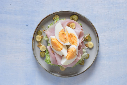 Open sandwich with salad, prosciutto cotto, pickles, corn and boiled egg