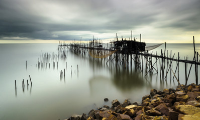 Traditional bamboo fisherman jetty during windy and moving clouds sunset.
