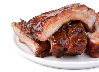Barbecued Ribs Close-up – A plate of pork spareribs with barbecue sauce. On a white plate and...