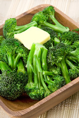 Broccoli with Butter – Fresh steamed broccoli, topped with a pat of butter, in a wooden bowl.