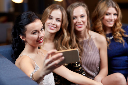 women with smartphone taking selfie at night club