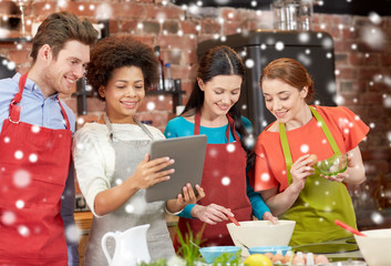 happy friends with tablet pc cooking in kitchen