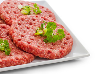 Raw hamburger slices on white plate