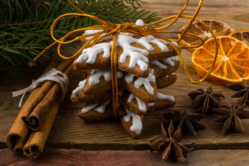 Christmas gift icing gingerbread, cookies, cinnamon, anise, fruit slices and fir branches on a wooden background, close up