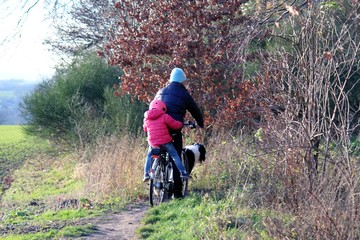 Naklejka premium Frau mit Kind auf dem Fahrradgepäckträger in der Natur