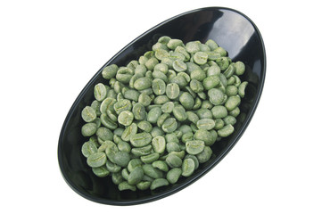 Black bowl with green coffee beans on the white
