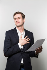 Blond-haired businessman puts his hand on his chest and feels a sigh of relief while in front of a gradient background