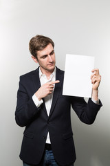 Blond-haired european businessman shows something on a piece of paper while in front of a gradient background
