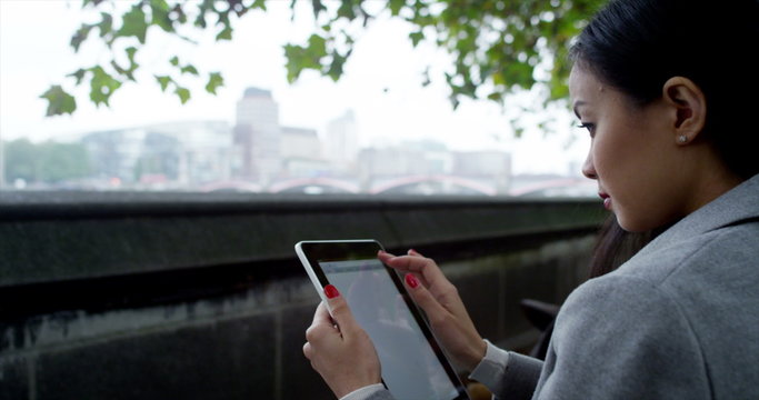 Attractive professional woman using computer tablet in city park