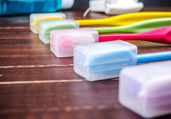 Set of colorful toothbrushs with mountwash and dental floss on wooden board