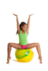 Fototapeta na wymiar a beautiful dark-skinned girl performs gymnastic exercise on a yellow ball. girl raised his hands, smile, joy,