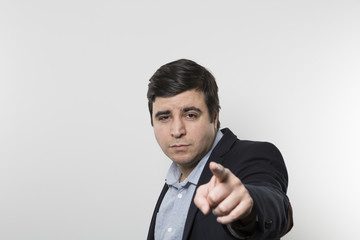 Dark-haired european businessman with a convincing look points directly at the camera while in front of a gradient background