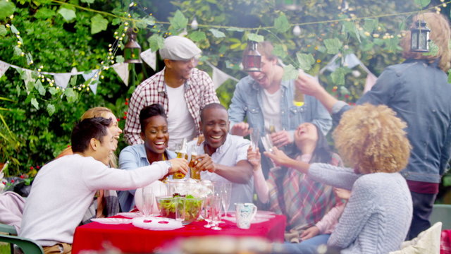  Happy mixed ethnicity group of friends laughing & drinking beer at bbq party