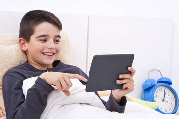 child playing in bed with tablet euphoric