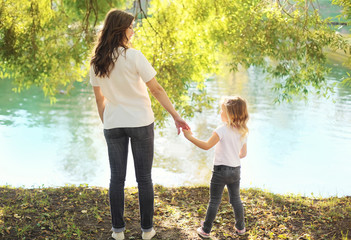 Happy mother and child daughter holding hands together in summer