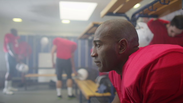  portrait of serious American football player in team locker room