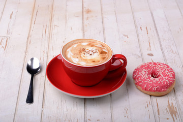  Cup of coffee, spoon and donut on wooden surface 