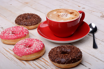 Cup of coffee and donuts on wooden surface 
