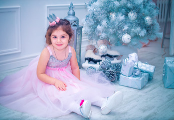 little girl dressed in beautiful fashion white flower dress posing near Christmas tree