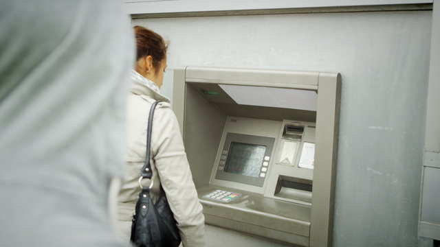  Suspicious character waits behind a woman as she takes money from ATM machine
