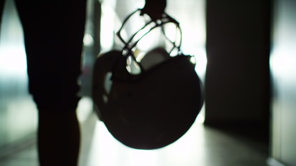 American football player walks alone through stadium tunnel - Powered by Adobe
