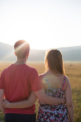 Young couple enjoying the sunset in the meadow