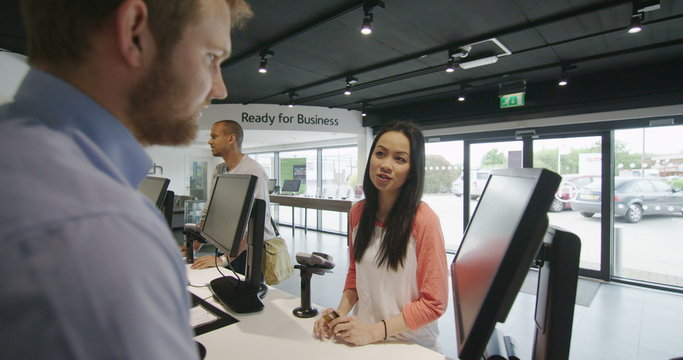 Helpful staff serving customers in consumer electronics store showroom
