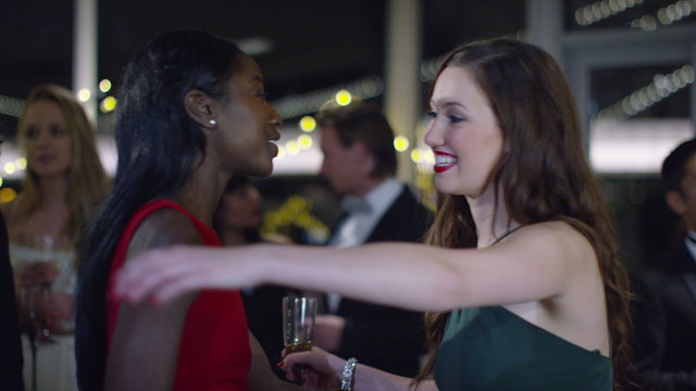  Attractive female friends at sophisticated party embrace and chat together