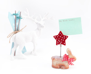 Christmas figurines; in front and in focus is rabbit with Christmas star and attached wish list; reindeer with skis is blurred in background

