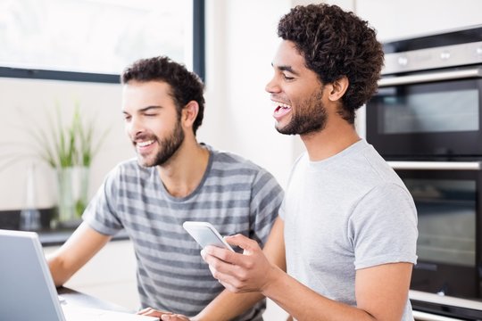 Smiling gay couple using technology at home