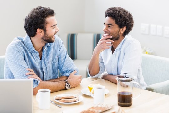 Smiling gay couple having breakfast at home