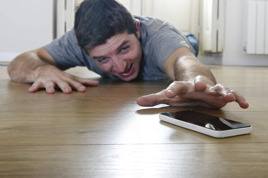 man trying to reach mobile phone creeping on the ground in smart phone and internet addiction concept