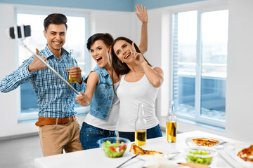Dinner Party At Home. Friends Having Fun, Taking Self-portrait Photo Using Smartphone Selfie Stick,...