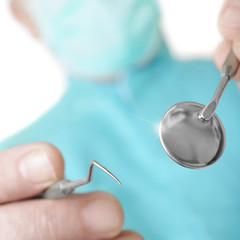 Hands of the dentist with a mirror and hook - Square composition