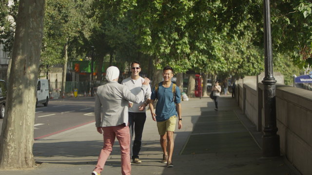  Happy casual male friends chatting as they walk through the city