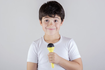 niño cantando con un microfono - obrazy, fototapety, plakaty