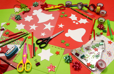 Arts and craft supplies for Christmas. Red and green color paper, pencils, different washi tapes, craft scissors, cardboard bell cut and decorations.
