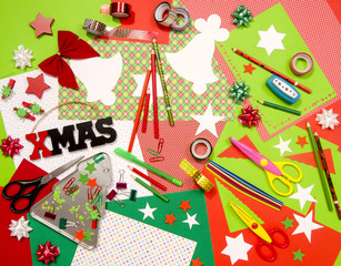 Arts and craft supplies for Christmas. Red and green color paper, pencils, different washi tapes, craft scissors, cardboard cuts, festive xmas supplies for decoration.