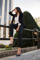 Businesswoman. / Business woman posing on a break from work. The woman is wearing a black suit with white shirt. 
