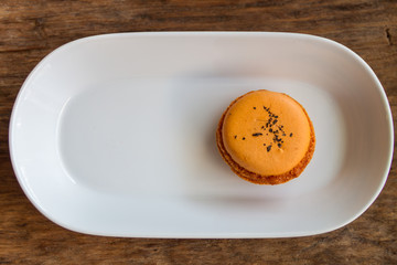 Tasty orange Thai tea macaroons on white dish