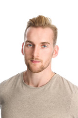 An attractive healthy man standing against a white background wearing a beige t-shirt.