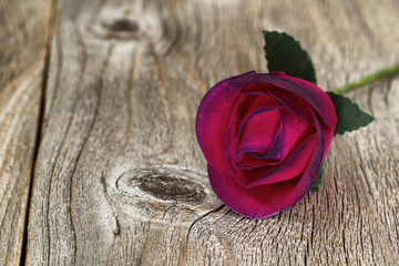 Close up of single wooden red rose on aged wood