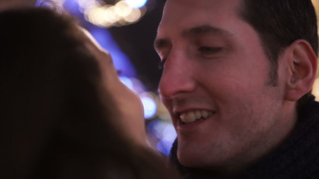 Close up of romantic couple kissing on city street at Christmas time. Shot on RED Epic.