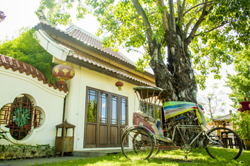 Fototapeta na wymiar Chinese building architecture and old rickshaw in tree shade