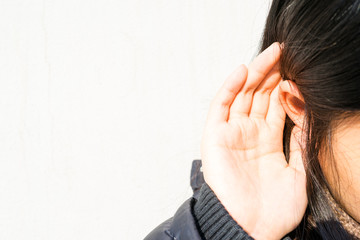 Image of listening, with a girl putting her hand on ear