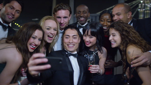  Happy attractive group of friends at a party pose to take a selfie together
