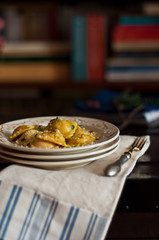tre piatti impilati con ravioli di patate americane sopra vecchio baule, forchetta, strofinaccio e libri sullo sfondo 
