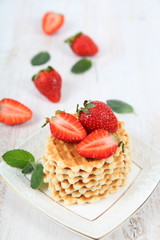 Waffles with strawberries on a wooden table